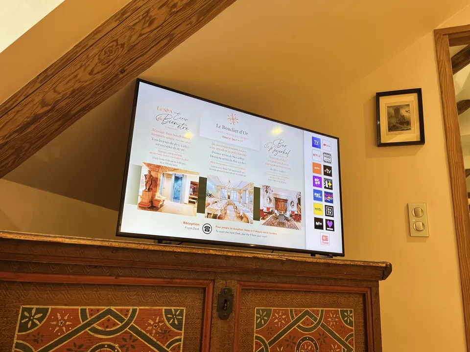 Téléviseur mural allumé dans une chambre mansardée.
